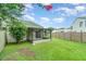 A view of the green backyard with a screened patio and wooden fence, under a partly cloudy sky at 1301 Winter Green Way, Winter Garden, FL 34787