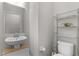 A neutral powder room featuring a modern floating sink, toilet and a three-tier metal shelf at 14242 Desert Haven St # Ge, Windermere, FL 34786