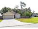 Charming one-story home with an attached garage, lush green lawn, and mature trees at 1436 Swan Ct, Kissimmee, FL 34759