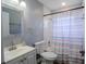 Clean bathroom with white vanity, toilet, tiled shower with colorful curtain at 2005 Dalton Ave, Deltona, FL 32725
