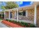 Charming covered front porch with seating, brick facade, and manicured landscaping at 2005 Dalton Ave, Deltona, FL 32725
