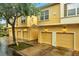 Charming yellow townhomes with individual garages, complimented by lush trees and colorful brick-lined driveway at 2820 Oakwater Dr # 2820, Kissimmee, FL 34747