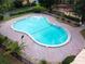 Aerial shot of a sparkling outdoor pool surrounded by a brick patio and tropical landscaping at 2850 N Powers Dr # 74, Orlando, FL 32818