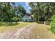 Peaceful view of a light blue home with a spacious green lawn and plenty of natural tree coverage at 3580 Ne 160Th Ln, Citra, FL 32113