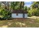 Light blue shed with a brown roof and decorative door amidst lush greenery and foliage at 3580 Ne 160Th Ln, Citra, FL 32113