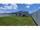 View of the fenced backyard with green grass and solar panels on the roof of the house at 394 Pentas Ln, Haines City, FL 33844