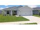 Charming single-story home featuring a manicured lawn, two car garage, and inviting entrance at 394 Pentas Ln, Haines City, FL 33844