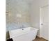 Freestanding bathtub with white tile accent wall and wood flooring in the Primary bathroom at 5627 Orange Orchard Dr, Winter Garden, FL 34787