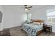 Bedroom with wood floors and ceiling fan features a comfortable bed, accent chair, and bright windows at 5627 Orange Orchard Dr, Winter Garden, FL 34787
