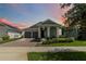 Beautiful single-story home with a brick driveway, a two-car garage, and a charming column-lined front porch at sunset at 5627 Orange Orchard Dr, Winter Garden, FL 34787