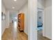 Bright hallway with wood-look flooring and a stylish wooden bookshelf, leading to a bedroom and the home's other areas at 5627 Orange Orchard Dr, Winter Garden, FL 34787