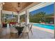 Covered outdoor dining area with a stone wall, views of the pool, lush landscaping, and an umbrella at 5801 Marleon Drive Marleon Drive, Windermere, FL 34786