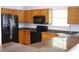 Modern kitchen with black appliances, wooden cabinets, and granite countertops, perfect for cooking at 6500 Abercrombie Ct, Orlando, FL 32835