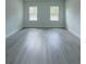 Empty bedroom showcasing gray wood-like flooring and natural light from two windows at 6516 Sw 149 Th Lane Rd, Ocala, FL 34473