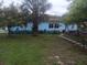 Charming light blue home featuring a manicured lawn and lush trees and landscaping at 833 Channing Rd, Lakeland, FL 33805