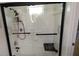 Modern shower featuring sleek black hardware, white tile, a built in seat, and safety handles at 833 Channing Rd, Lakeland, FL 33805