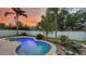 Beautiful backyard swimming pool, tropical foliage, and a stunning orange sunset at 912 Pickfair Ter, Lake Mary, FL 32746