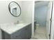 Bathroom with a marble countertop, grey vanity, oval mirror and doorway to the toilet room at 9551 Lake Douglas Pl, Orlando, FL 32817