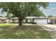 Charming single-story home with a well-maintained lawn and mature shade tree in front of the house at 9551 Lake Douglas Pl, Orlando, FL 32817