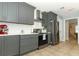 A modern kitchen featuring sleek grey cabinets, stainless steel appliances, and a clean white backsplash at 9551 Lake Douglas Pl, Orlando, FL 32817