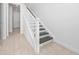 Bright and airy staircase featuring white banisters, modern gray treads, and neutral tile flooring at 10072 Sunnifa Aly, Orlando, FL 32832