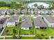 An aerial view of a residential neighborhood featuring well-maintained homes, green lawns, and a picturesque lake in the background at 12216 Encore At Ovation Way, Winter Garden, FL 34787