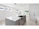 Modern kitchen island with a stainless steel sink, dishwasher, gray cabinets, and white countertop with backyard view at 12216 Encore At Ovation Way, Winter Garden, FL 34787