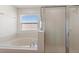 Bathroom featuring a large soaking tub and glass-enclosed shower with natural light at 148 Miro Dr, Davenport, FL 33837