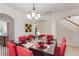 Formal dining room featuring an elegant chandelier and dark wood table set for dinner with red accents at 148 Miro Dr, Davenport, FL 33837