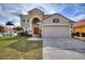 Charming two-story home featuring a red tile roof, arched entryway, and well-maintained landscaping at 148 Miro Dr, Davenport, FL 33837