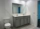 Bathroom showcasing double vanity, tiled floors, and toilet with a door to the hallway at 1950 Birnham Wood Bnd, Kissimmee, FL 34746
