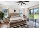 A primary bedroom features a gray upholstered bed, a ceiling fan, and sliding glass doors to the backyard at 19606 Reynolds Pkwy, Orlando, FL 32833