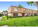 Charming townhouse featuring a manicured lawn, red shutters, and a brick and wood facade at 200 St Andrews Blvd # 601, Winter Park, FL 32792