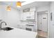 Clean kitchen featuring white appliances and cabinets, accented by pendant lights and a tiled backsplash at 200 St Andrews Blvd # 601, Winter Park, FL 32792