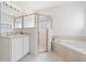 Bright bathroom features a glass enclosed shower, soaking tub, and double sink vanity at 20130 Sunset Landing Ave, Groveland, FL 34736