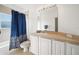 Bright bathroom featuring a shower-tub combination, blue shower curtain, and a large vanity mirror with lights at 20130 Sunset Landing Ave, Groveland, FL 34736