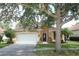 Well-maintained one-story home with stucco exterior, a two-car garage, and mature trees shading the front yard at 203 Brookgreen Way, Deland, FL 32724