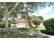 Charming home with manicured lawn, stone accents, mature trees, and attached two car garage at 203 Brookgreen Way, Deland, FL 32724