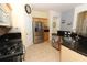 Kitchen showcasing stainless steel appliances, wood cabinets, and black countertops with a stylish tile backsplash at 203 Brookgreen Way, Deland, FL 32724