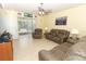 Comfortable living room featuring reclining sofa set, ceiling fan, and sliding glass door to patio at 203 Brookgreen Way, Deland, FL 32724