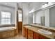 A primary bathroom featuring double sinks, a soaking tub, a glass block window, and a walk-in shower at 205 Trail Bridge Ct, Winter Garden, FL 34787