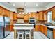 Traditional kitchen featuring brick accents, stainless steel appliances, tile countertops, and wooden cabinets at 205 Trail Bridge Ct, Winter Garden, FL 34787