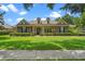 Charming stone home featuring a tile roof, manicured lawn, and lush landscaping at 25554 Hawks Run Ln, Sorrento, FL 32776