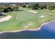 Scenic golf course view with lush green fairways, sand traps, mature trees and a beautiful blue lake along the edge at 25554 Hawks Run Ln, Sorrento, FL 32776