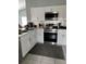 Well-lit kitchen with stainless steel appliances, white cabinets, and decorative tile backsplash at 2833 Woodruff Dr, Orlando, FL 32837