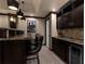 Basement bar area with granite counters, dark cabinetry, pendant lighting, and black leather bar stools at 2937 Butler Bay N Dr, Windermere, FL 34786