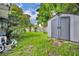 Landscaped backyard featuring lush greenery, mature trees, and a storage shed for garden essentials at 3010 Brandywine Dr, Orlando, FL 32806