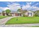 Inviting single-story home with a curved driveway leading to the entrance, showcasing a lush green lawn and garden details at 3010 Brandywine Dr, Orlando, FL 32806