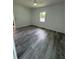 Bright bedroom featuring sleek gray wood floors, a ceiling fan, and a window that streams in plenty of natural light at 320 W Necho Ave, Lake Alfred, FL 33850