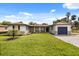 Charming single-story home with stone accents, a well-manicured lawn, and a blue garage door at 338 Henry Butts Dr, Daytona Beach, FL 32114